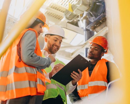 Three people discussing a plan at a factory Three people discussing a plan at a factory